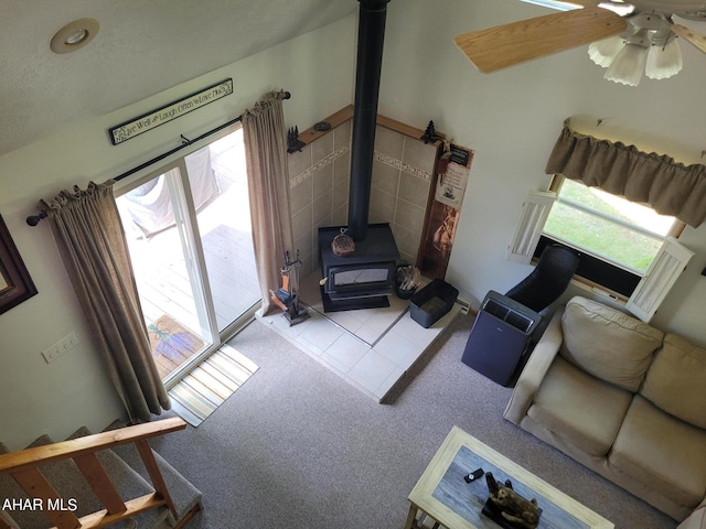 living room featuring tile patterned floors, ceiling fan, a wood stove, and a wealth of natural light