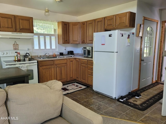 kitchen featuring brown cabinetry, white appliances, a sink, and under cabinet range hood