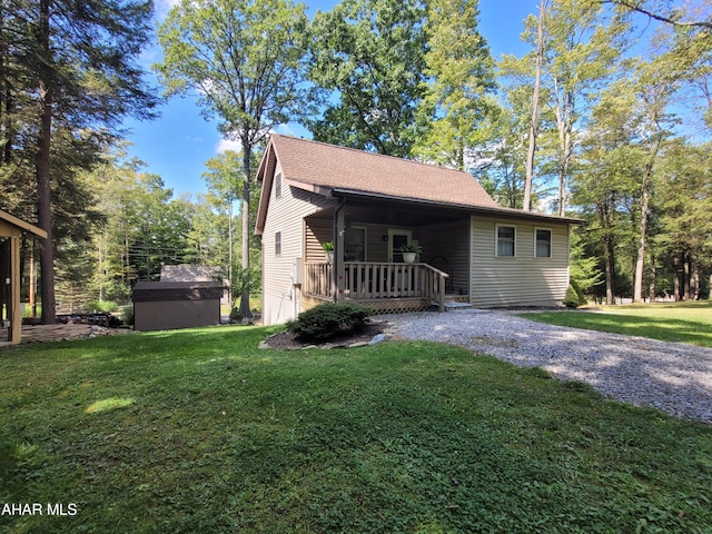 view of front of home featuring a porch, a front yard, and a storage shed