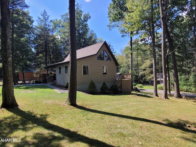 view of side of property with a yard, a wooden deck, and stairs