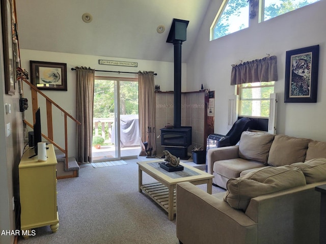 living room with high vaulted ceiling, a wood stove, carpet flooring, and stairs