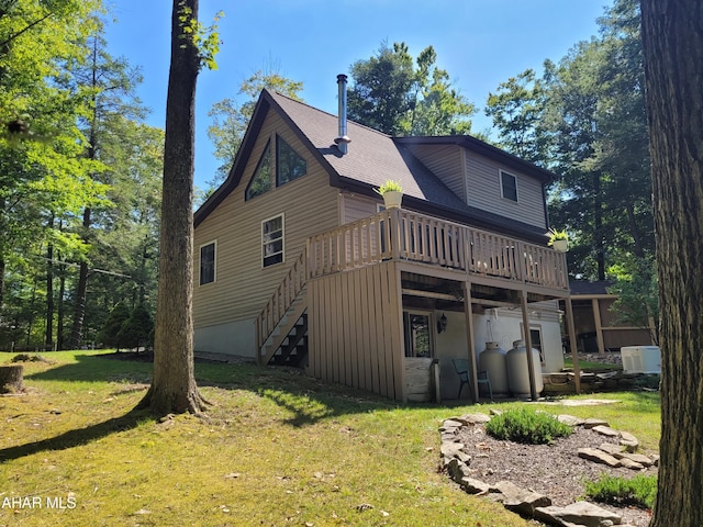 rear view of property featuring a wooden deck and a lawn