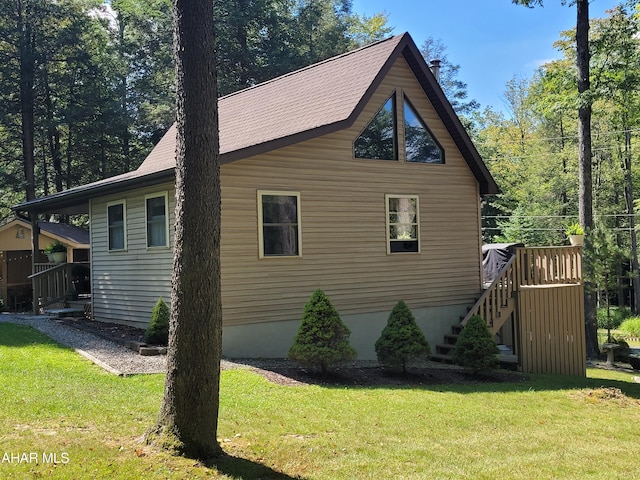 view of side of property with roof with shingles, a yard, and stairway