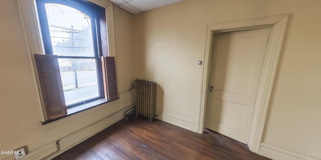 spare room with radiator heating unit and dark wood-type flooring