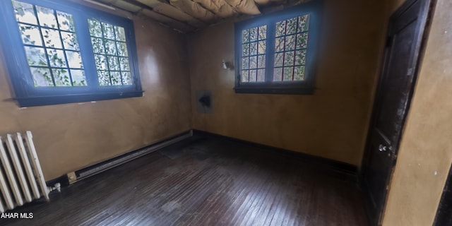 empty room with radiator and dark hardwood / wood-style floors