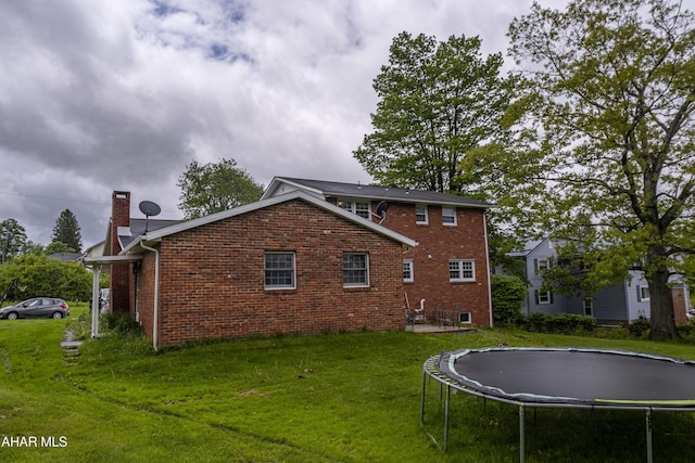 829 Ashcroft Ave, Cresson, PA 16630 - back of property featuring a trampoline, brick siding, a lawn, and a chimney