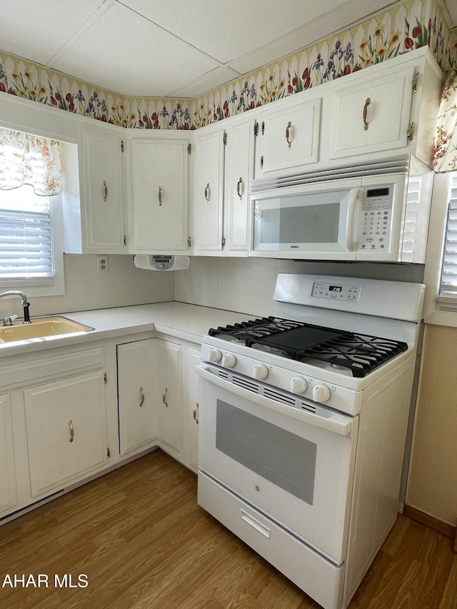 kitchen featuring white cabinetry, sink, white appliances, and light hardwood / wood-style floors