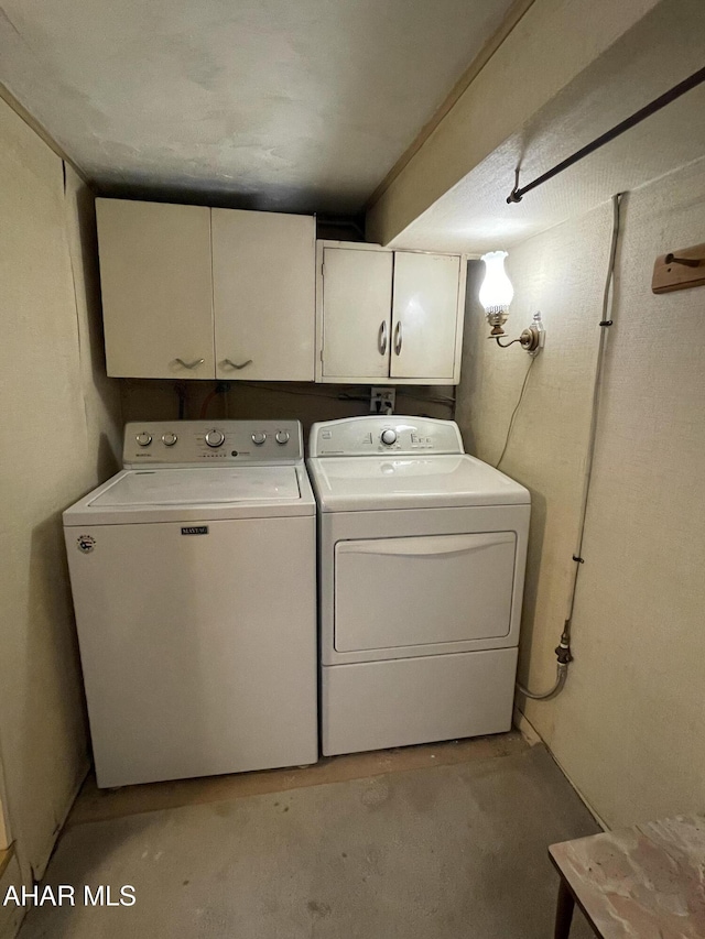 clothes washing area with cabinets and washing machine and dryer