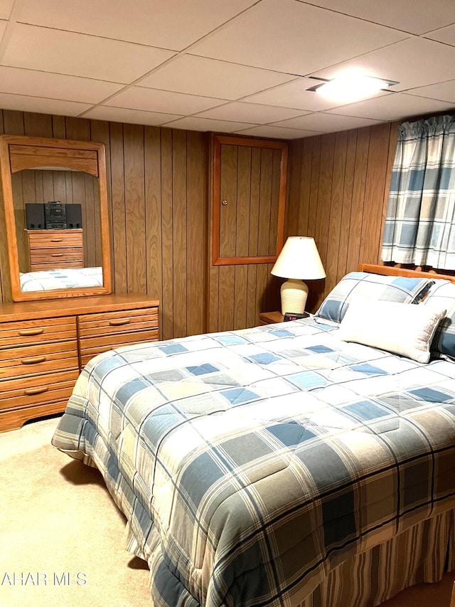 carpeted bedroom featuring a paneled ceiling and wooden walls