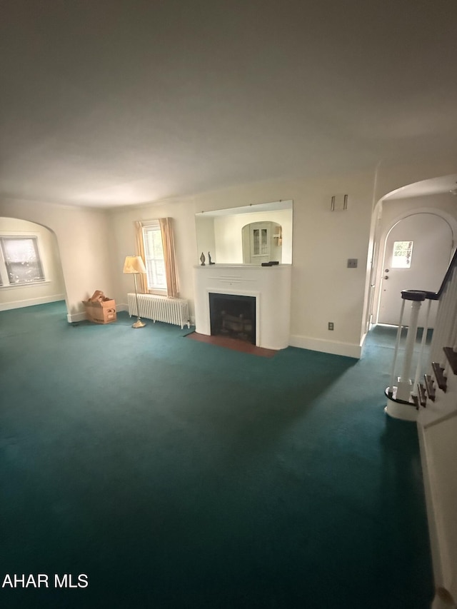 414 27th Ave, Altoona, PA 16601 - unfurnished living room featuring arched walkways, radiator, a fireplace, baseboards, and carpet flooring