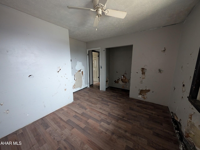 unfurnished room featuring dark hardwood / wood-style flooring, ceiling fan, and a textured ceiling