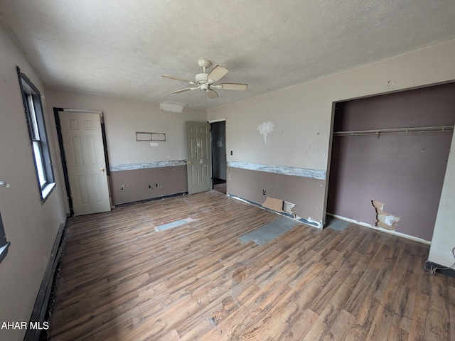 unfurnished bedroom featuring hardwood / wood-style flooring, ceiling fan, a textured ceiling, and a closet