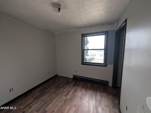 spare room featuring dark hardwood / wood-style floors, a textured ceiling, and baseboard heating