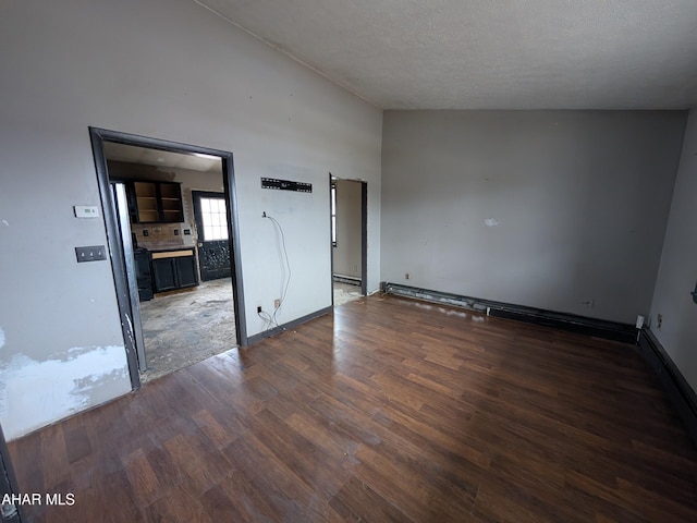 empty room with dark hardwood / wood-style flooring and a textured ceiling