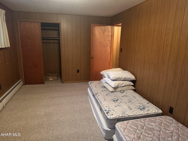 carpeted bedroom featuring wood walls, a baseboard heating unit, and a closet