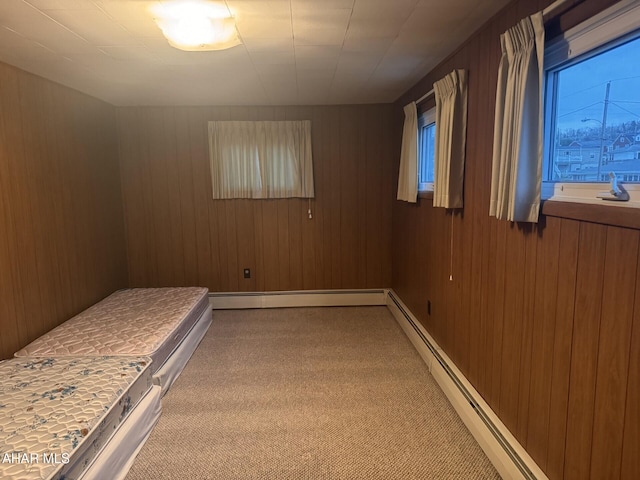 unfurnished bedroom featuring carpet floors, a baseboard heating unit, and wood walls