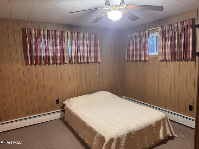 bedroom with carpet floors, baseboard heating, ceiling fan, and wooden walls