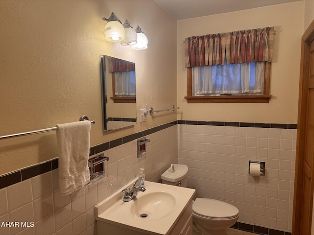 bathroom featuring vanity, tile walls, and toilet