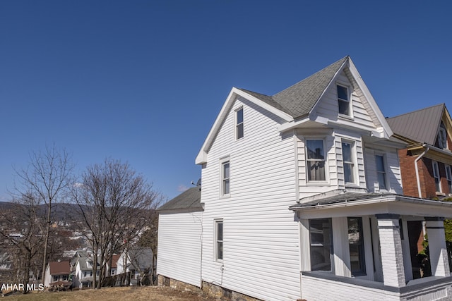 view of side of home with a shingled roof