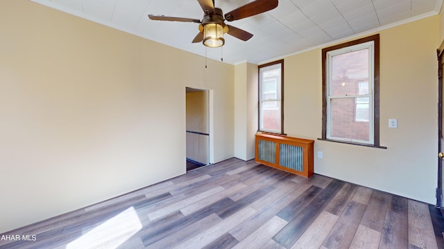 spare room with crown molding, radiator heating unit, wood finished floors, and ceiling fan