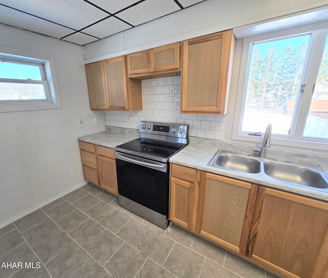 kitchen with a paneled ceiling, light countertops, electric range, decorative backsplash, and a sink