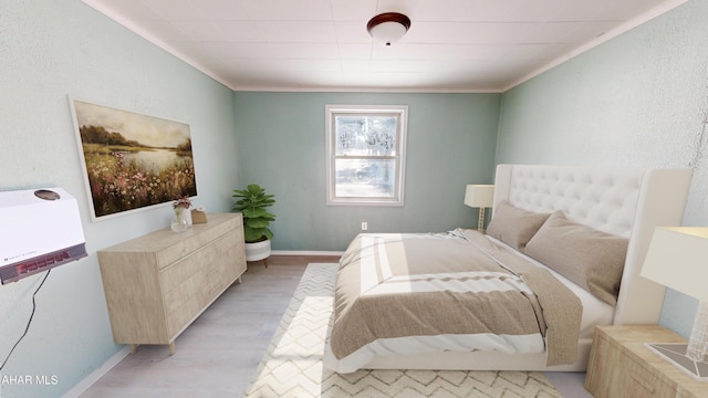 bedroom featuring baseboards, light wood finished floors, and crown molding