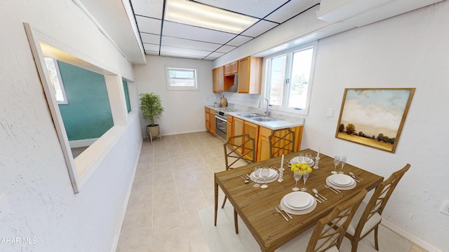 dining space featuring a paneled ceiling and baseboards