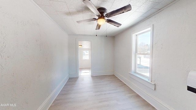 empty room featuring baseboards, a textured wall, and light wood finished floors