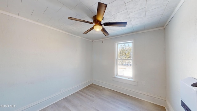 spare room with light wood-style floors, ornamental molding, baseboards, and a ceiling fan