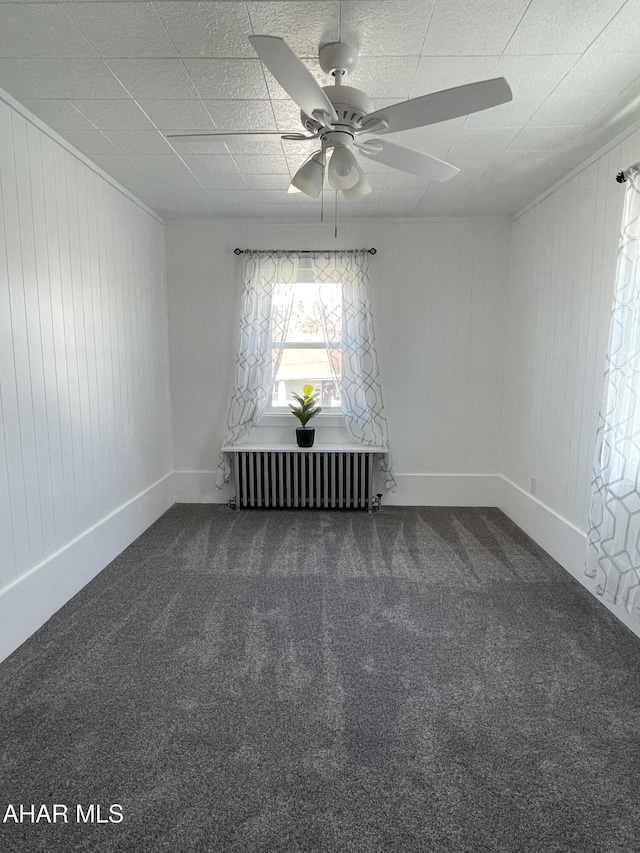 unfurnished room featuring carpet flooring, radiator, a ceiling fan, and baseboards