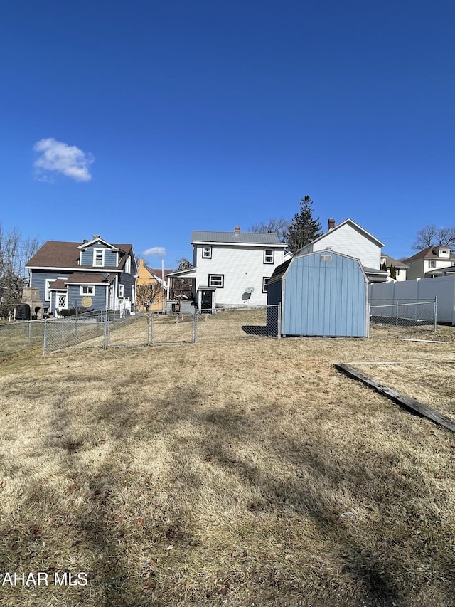 view of yard with a gate, a storage shed, an outdoor structure, and fence