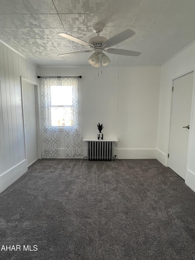 unfurnished room with radiator, a ceiling fan, and carpet floors