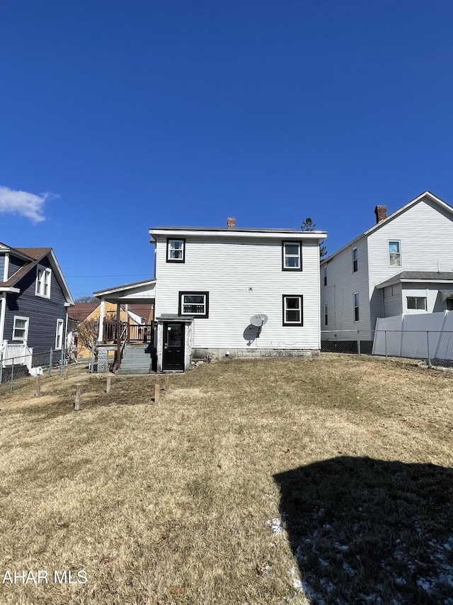 back of house with fence and a lawn