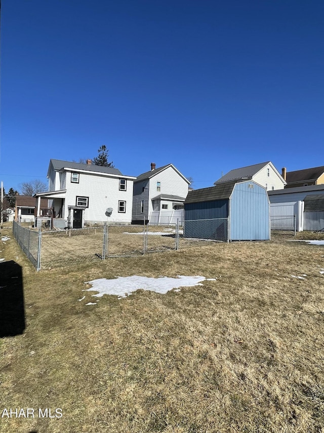 back of property with a storage shed, fence, and an outdoor structure