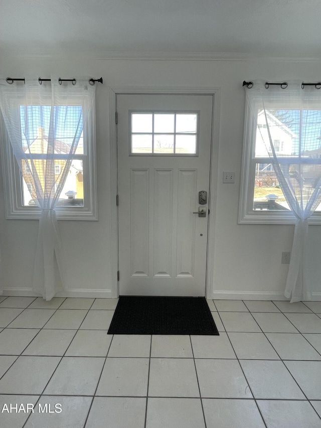 doorway to outside featuring light tile patterned floors, plenty of natural light, and baseboards