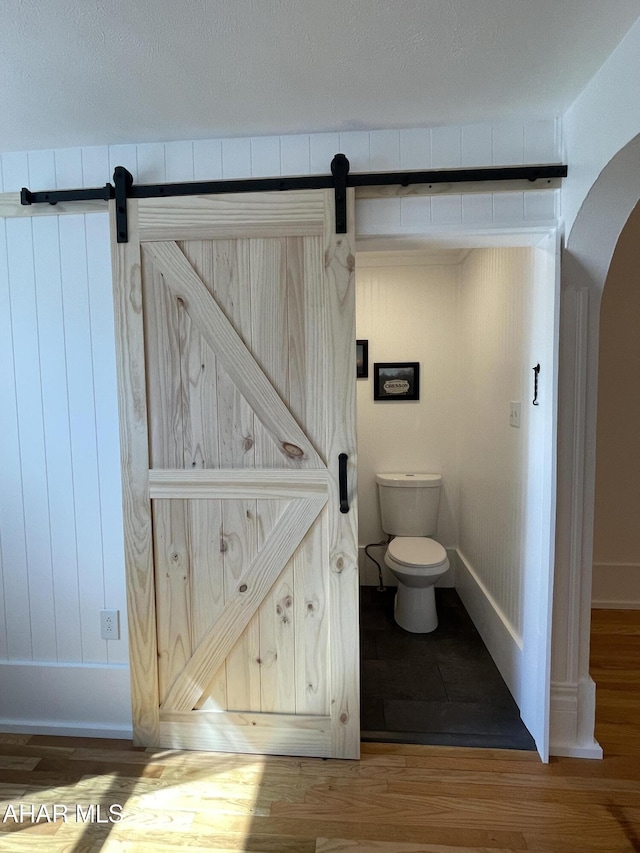 bathroom featuring toilet, wood finished floors, and baseboards