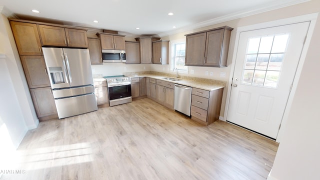 kitchen featuring crown molding, appliances with stainless steel finishes, sink, and light wood-type flooring