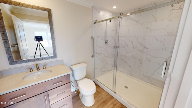 bathroom with crown molding, hardwood / wood-style floors, vanity, a shower with shower door, and toilet