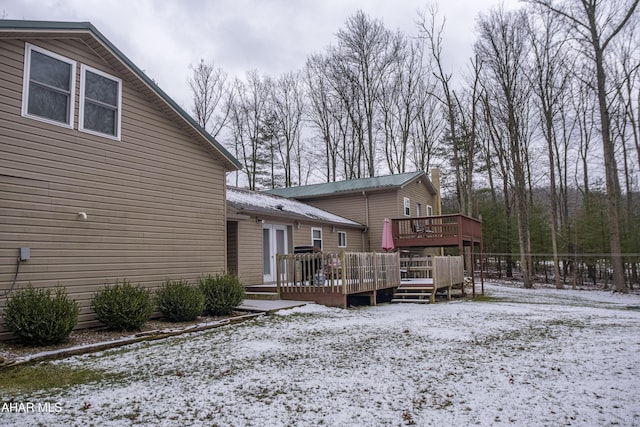 snow covered rear of property with a deck