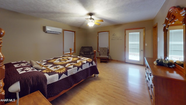 bedroom featuring ceiling fan, light hardwood / wood-style floors, access to outside, and a wall unit AC