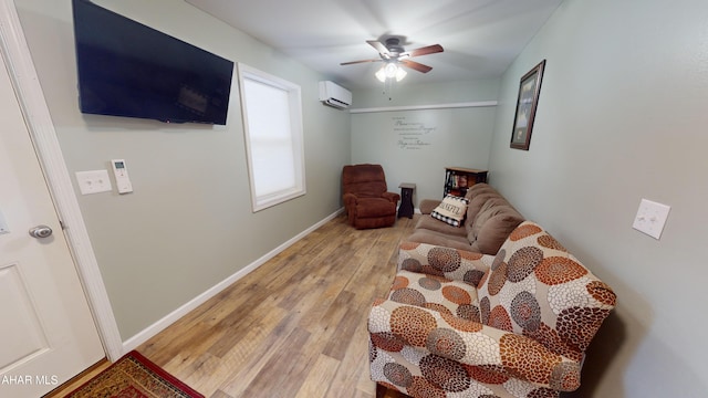 living area featuring a wall mounted air conditioner, ceiling fan, and light hardwood / wood-style floors