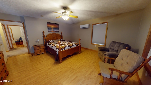 bedroom with a wall mounted air conditioner, ceiling fan, a textured ceiling, and light hardwood / wood-style flooring