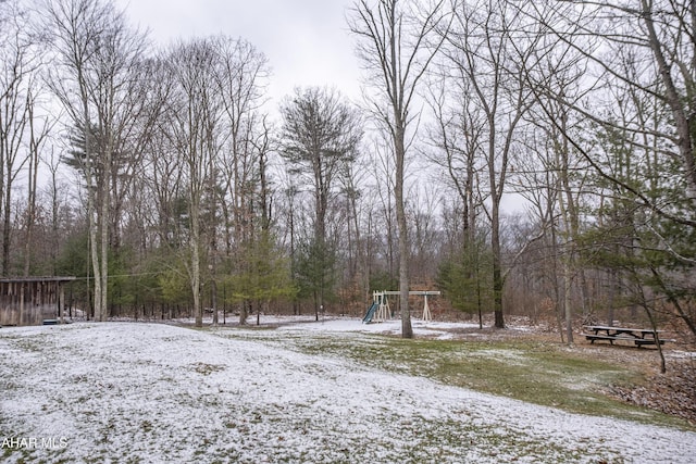 yard covered in snow featuring a playground