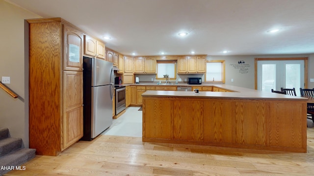 kitchen featuring kitchen peninsula, stainless steel appliances, light hardwood / wood-style floors, and sink