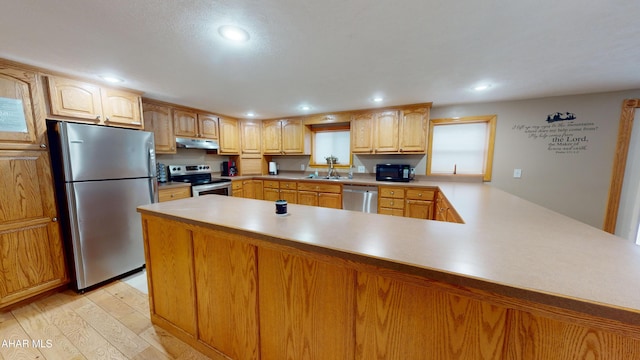 kitchen with kitchen peninsula, sink, stainless steel appliances, and light wood-type flooring