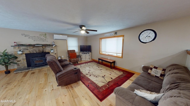 living room featuring a textured ceiling, light wood-type flooring, an AC wall unit, and ceiling fan