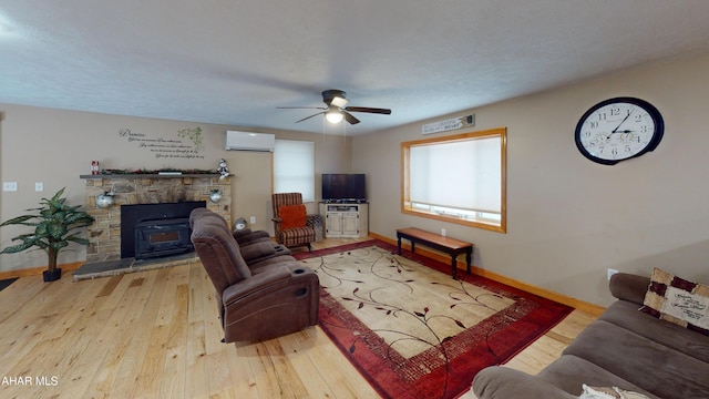 living room with an AC wall unit, ceiling fan, hardwood / wood-style floors, and a textured ceiling