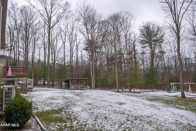 yard covered in snow with a deck and a playground