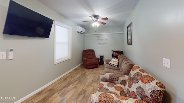 living area featuring a wall unit AC, ceiling fan, and light hardwood / wood-style floors