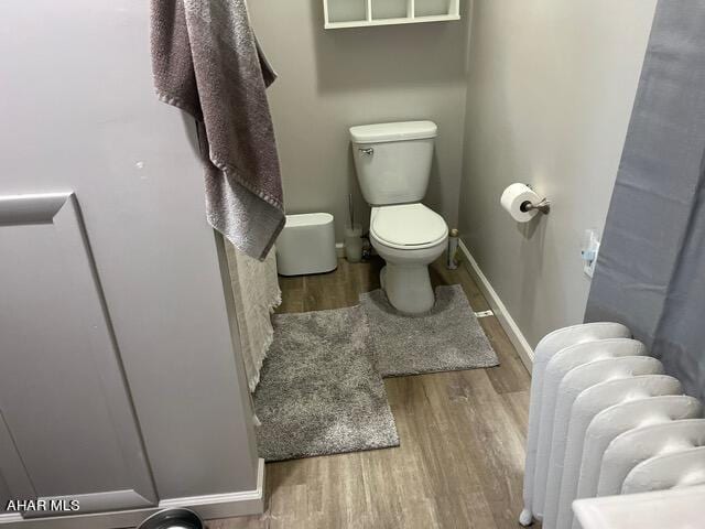 bathroom with toilet, wood-type flooring, and radiator